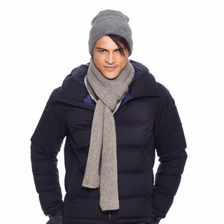 A man wearing winter clothing including a dark puffy jacket, a Marbled Scarf handmade in Nepal merino wool knit scarf, and knit hat.