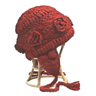 A handmade in Nepal Crochet Flower Heart Earflap Hat with floral patterns and a tassel, displayed on a stand.