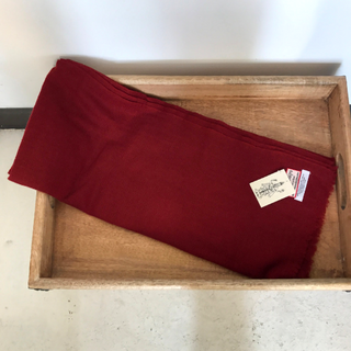 A red Solid Pashmina scarf from Nepal with a tag is laid out diagonally across a wooden tray.