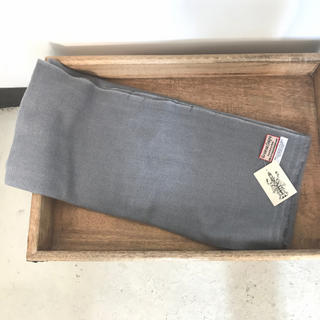 A folded gray Solid Pashmina Scarf with tags placed on a wooden tray.