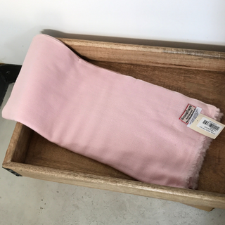 A pink Solid Pashmina scarf with a label is partially folded and placed inside a wooden drawer.