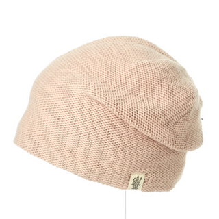 A pink knit beanie, The Depp Slouch, on a white background, perfect for preventing dry skin with its moisturizer-infused fabric.