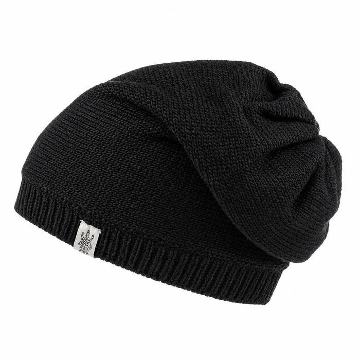 Hand Loom Dekalb Slouch is a black, hand-knit slouchy beanie with ribbed edging and a small white fabric tag on the front, shown against a plain white background.