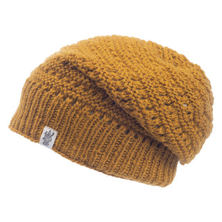 Displayed is the Boho Slouch, a mustard yellow, knitted beanie hat with a woven texture. The winter hat features a small white patch with a black logo sewn on the edge.