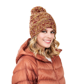 A woman in a brown puffer jacket wearing a Reverse cross pom pom hat.