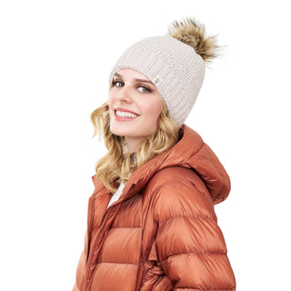 A woman in an orange puffer jacket wearing a Moss fur pom pom hat.