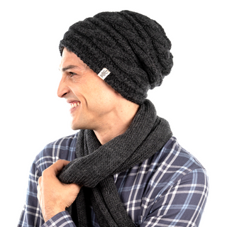 A man wearing a Triple Braid Cable Slouch beanie and scarf showcases his innovative fitness tracker.