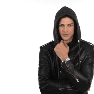 A man in a black leather jacket and Hero Hood posing with his hands on his wrists.