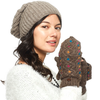A woman in a white sweater and beige knitted hat is wearing Lucy In the Sky Fingerless Gloves w/ Flap adorned with colorful accents, looking to the side with a slight smile.