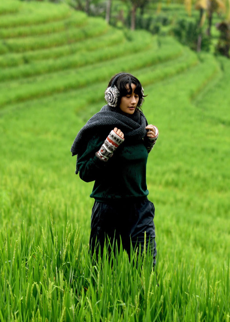 Woman wrapped in a charcoal knit scarf walking through rice terraces