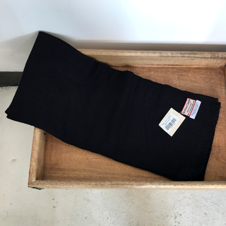 A pair of folded black pants with tags on them, placed neatly in a wooden tray alongside a luxurious Solid Pashmina scarf.