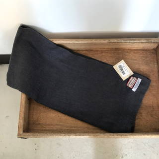 A folded dark grey Solid Pashmina Scarf with tags lying on a wooden tray.