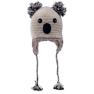 A hand-made Crochet Koala Hat with ear flaps and pom-pom details designed to resemble a koala face, isolated on a white background.