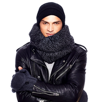 A man wearing a black knit hat, a large dark gray scarf, Hand Knit Fingerless Gloves With Button Flap and Fleece Lining, and a black leather jacket stands with his arms crossed against a white background.