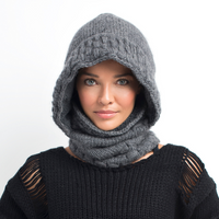 A person wearing the Hand Knit Legends Hood in gray merino wool and a black, textured sweater looks toward the camera with a neutral expression against a white background, showcasing this versatile unisex neckwarmer.