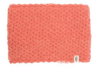 A salmon pink knitted fabric with a uniform pattern and a sherpa fleece lining, with the I See Stars Neckwarmer attached to the bottom right corner.