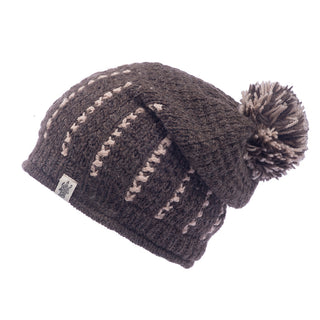 Handmade in Nepal, knitted Ferry slouch hat with a pom-pom and decorative lighter brown stripes, isolated on a white background.