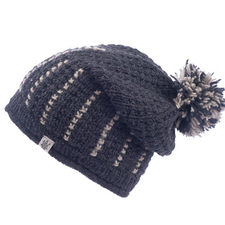 A knitted gray Ferry slouch hat with a pompom and decorative stitching, handmade in Nepal, isolated on a white background.