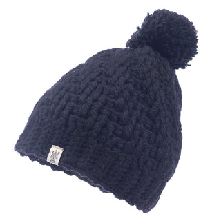 A black knitted beanie made of merino wool with a Swirl pom beanie on top.