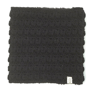 A square black Good Vibes Neckwarmer with a textured rose pattern on the surface, featuring a sherpa fleece layer for added comfort, and a visible manufacturer's tag on the lower right side.