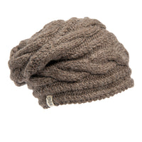 A Hand Knit Triple Braid Cable Slouch beanie in brown merino wool, featuring a classic chunky cable knit pattern, is displayed on a white background. The hat has a slouchy fit and a small metal tag sewn onto the edge.