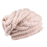 The Hand Knit Triple Braid Cable Slouch is a light pink, chunky knit hat featuring a braided cable pattern and a small white tag sewn onto the bottom edge, displayed against a white background.