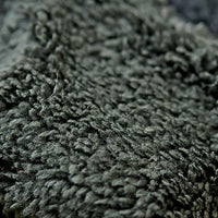 Close-up image of the Hand Loom Mandy Headband in dark green, showcasing its textured, soft, and fuzzy surface. Individual fibers and subtle color variations evoke the look of handmade Nepali textiles, highlighting the headband’s unique character.