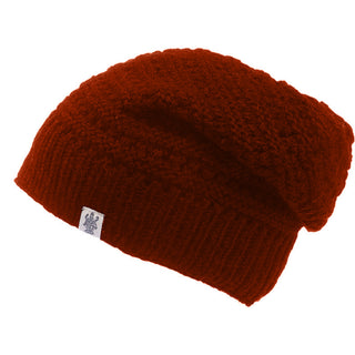 The Boho Slouch is a red knit beanie with a ribbed edge and a small white logo tag, shown against a white background—perfect for keeping cozy in winter.
