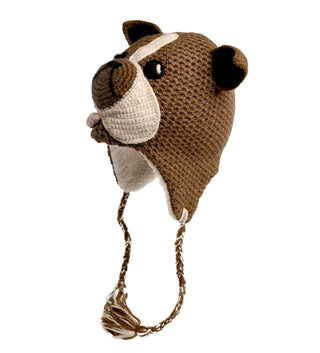 The Crochet Bulldog Hat is a brown and beige knitted hat, handmade in Nepal and designed to resemble the head of a dog. It features ears, a snout, and embroidered nose and eyes. Crafted from crochet wool with braided tassels hanging from the ear flaps and a tongue sticking out, it also has a cozy sherpa lining. The background is plain white.