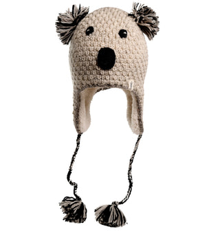 The Crochet Koala Hat is hand-made in Nepal from wool and features ear flaps, a black nose, and black eyes. It has two pom-poms on the top representing ears and two braided strings with pom-poms at the ends.