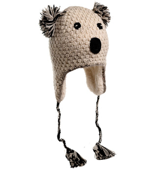 Introducing the Crochet Koala Hat: a hand-made in Nepal knitted hat, designed to resemble a lovable koala. Featuring two pom-pom ears, black stitched eyes, and a black nose, this hat also includes ear flaps with braided tassels hanging down. Crafted from 100% wool for warmth and comfort, the yarn is a delightful blend of cream and brown colors.