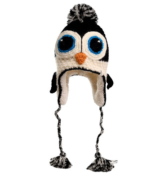 The Crochet Penguin Hat is designed to resemble a penguin, featuring large blue eyes, an orange beak, and ear-covering flaps. Hand-made in Nepal from high-quality wool, the hat also includes black and white braided tassels that end in pom-poms.