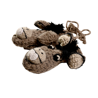 The Crochet Donkey Mittens, handmade in Nepal, are a charming pair of brown knit mittens designed to resemble donkey heads, complete with white snouts, black button eyes, and small black manes. For added convenience, they are connected by a yarn string.