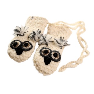 A pair of white crochet baby mittens with an owl design, hand-made in Nepal. The mittens feature black and grey detailing on the owl faces, a joined string for securing them, and are crafted from 100% wool.