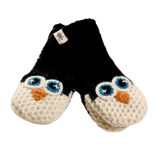 A pair of black and white knitted baby booties designed to resemble penguins with blue eyes and orange beaks. The soles are textured, and a small tag is attached to one bootie. Hand-made in Nepal, these adorable booties capture the essence of Crochet Penguin Mittens with intricate details.