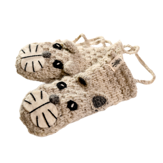 The Crochet Shmil the Cat Mittens are a pair of hand-made, beige crocheted animal puppet mittens from Nepal, designed to resemble cat faces. They feature large white patches with black stripes on the front and black button-like eyes. Connected by a string, these charming mittens add a playful touch to any outfit.