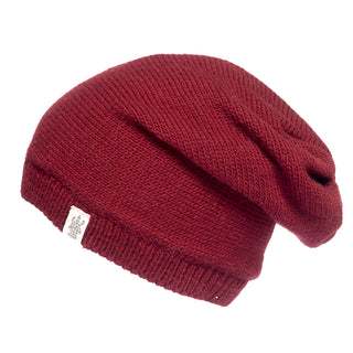 The Hand Loom Dekalb Slouch is a red, hand-knit merino wool slouch hat with a small white fabric tag on the cuff, shown against a white background.
