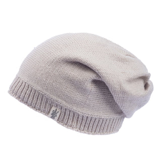 Displayed against a plain white background, the Dekalb Slouch is a knitted beige beanie made of soft Merino wool. It features a relaxed design and a small tag with a logo on the brim, making it an ideal cold-weather accessory.