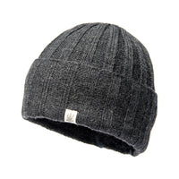 The Hand Loom Ribbed Beanie is a dark gray, ribbed knit merino wool hat featuring a fold-over cuff and a small white rectangular tag on the front, shown against a white background.