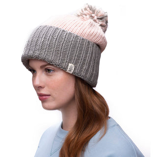 A woman wearing a handmade beanie with a pink and grey Masha pom slouch.