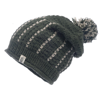 A dark green, handmade in Nepal, merino wool knitted Ferry slouch beanie with a pompom and white accent stitching, displayed against a white background.