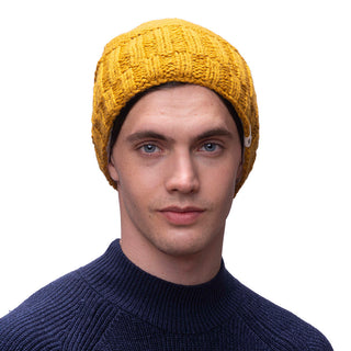 A man wearing a yellow *Percy beanie* knitted from merino wool.