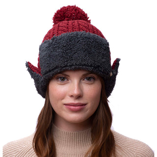 A woman wearing a red and gray Sherpa trapper hat with pom.
