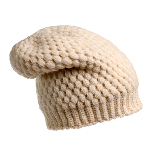 The Bubble Hat, a cream-colored knitted winter beanie with a bubble-knit design and slightly slouched style, is displayed against a white background.