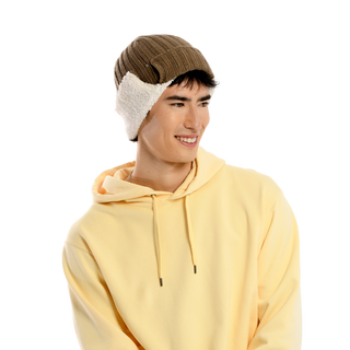 A person wearing a yellow hooded sweatshirt and the Astor Hat, a brown knit winter hat with white ear flaps, smiles while looking to the side. The background is plain and dark.