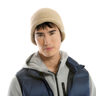 A man with dark hair wearing a Baxter Hat, light gray hoodie, and dark blue puffer vest is looking directly at the camera against a solid black background. He has a neutral facial expression.