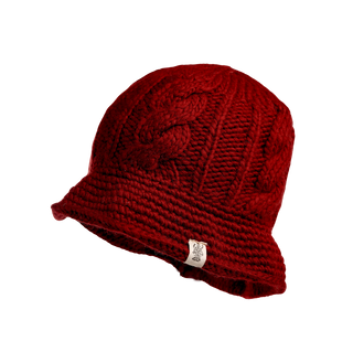 The Nostrand Hat is a cozy red knitted wool hat crafted from soft merino wool, showcasing a thick texture with an eye-catching cable knit design on the side. It features a small white tag with the logo and includes a wide brim for added style and snug fit, making it an essential addition to any winter wardrobe.