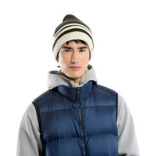 A person is wearing a grey hoodie under a blue quilted vest, complemented by the McGuinness Hat, a knitted beanie with white, black, and grey stripes. The background is plain black.