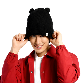 A person is wearing a Bear Cub Ears Hat, a white collared shirt, and a red jacket. The person is smiling and holding the edges of the hat with both hands. The background is plain and black.