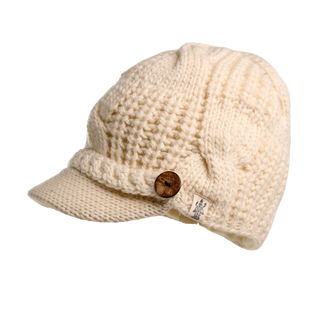 The Broadway Hat is a white cable knit hat with a short brim and a decorative wooden button on the side. This winter essential features a textured pattern and includes a small tag with text, making it both stylish and functional.